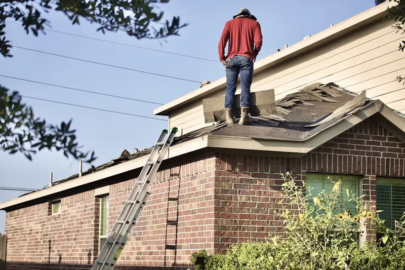 Professional roofer working on a residential roof in Artemas